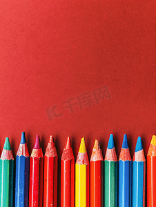 奶瓶蜡笔摄影照片_红色背景上的彩色蜡笔绘图配件