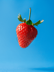 悬浮背景摄影照片_蓝色背景中悬浮的草莓浆果