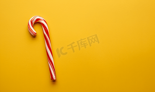 红色黄色喜庆摄影照片_黄色背景复制空间上的一根圣诞棒棒糖