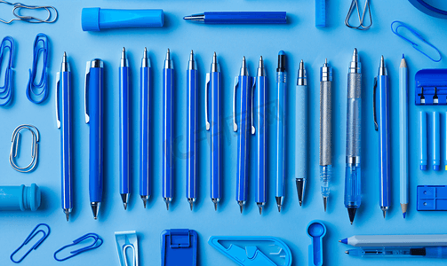 钢笔、铅笔、圆规、回形针排成线全部为蓝色背景为