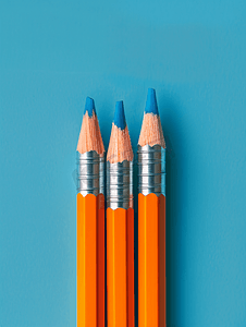 寒假招生艺术字摄影照片_蓝色背景上带橡皮擦的橙色铅笔