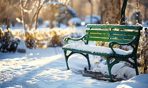 冬季积雪覆盖的城市花园中的绿色长椅