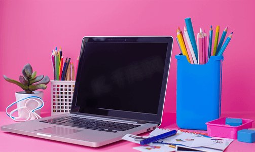 笔和纸摄影照片_蓝色支架上的笔记本电脑笔和彩色铅笔以及粉红色上的白色贴纸