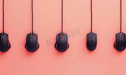黑色电脑鼠标挂在柔和的桃色背景上