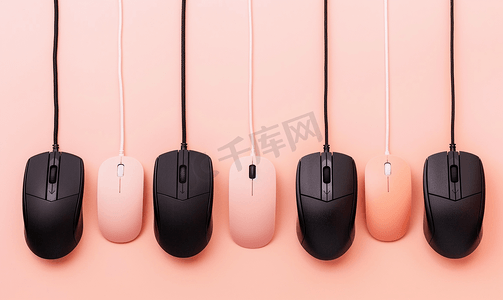 黑色电脑鼠标挂在柔和的桃色背景上