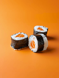 美食背景寿司摄影照片_亮橙色背景中的经典黑色寿司卷