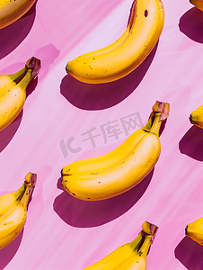 黄色几何创意摄影照片_粉红色背景上香蕉的几何图案从顶部看