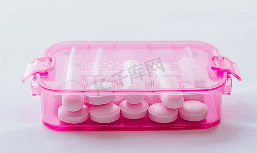 白色背景中粉色药丸盒中的药丸