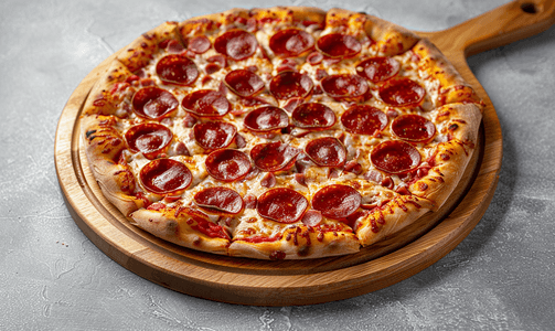 美味香肠摄影照片_灰色混凝土背景中木盘上放着美味的意大利辣香肠披萨