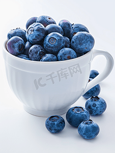 白汁河豚摄影照片_蓝莓是白色背景中白杯中的成熟浆果