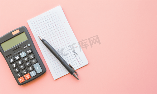 粉红色背景上计算器空白网格纸笔记本和钢笔的平铺