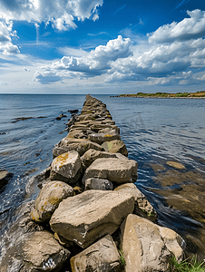 轻松有趣摄影照片_丹麦阳光明媚的风景中石堤伸入海岸附近的水中