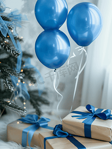 儿童节日礼物摄影照片_树下带蓝色蝴蝶结的节日礼物带气球的玻璃圣诞节和新年