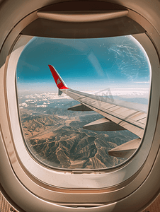 飞行窗口摄影照片_从机翼上的飞机窗户看到天空和云彩
