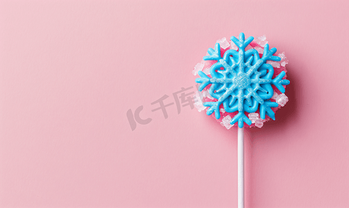 气球棒棒糖礼物盒摄影照片_粉红色背景中雪花形状的蓝色棒棒糖
