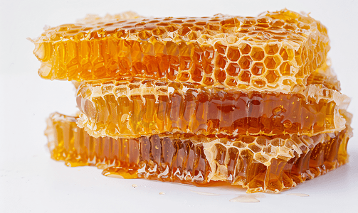 多边形的背景摄影照片_白色背景上的蜂蜜梳甜蜂蜜产品梳子里的甜蜂蜜