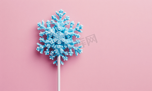 粉红色背景中雪花形状的蓝色棒棒糖