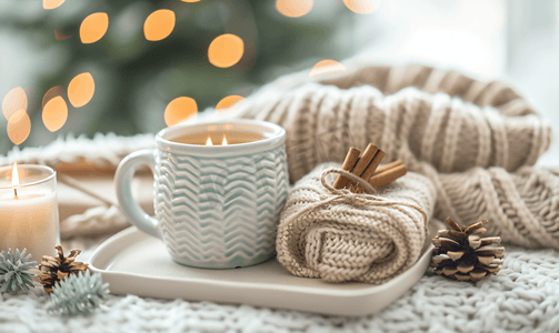 桌子家居摄影照片_茶杯温暖毛衣蜡烛赠送礼物和杉树冬季家居舒适概念