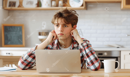 疲惫或有压力的年轻青少年坐在笔记本电脑前准备考试