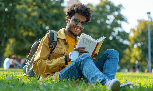 坐在公园草地上手捧咖啡读书的搞笑学生