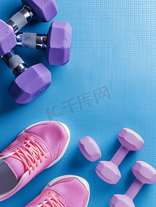 蓝色氯丁橡胶垫上的一对紫色哑铃运动手套和粉色运动鞋