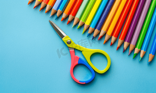 蓝色背景中的塑料剪刀和彩色木铅笔