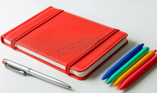 红色日记笔记本和彩色笔孤立在白色背景上