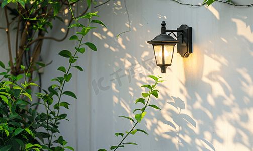 团圆灯笼摄影照片_垂悬在白墙上的黑色花园壁灯