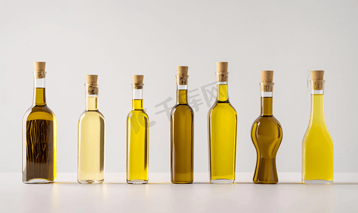 玻璃透明瓶子摄影照片_白色背景上装有橄榄油的一组瓶子