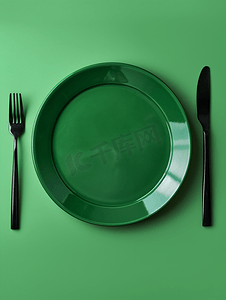 空圆形绿色陶瓷板和金属叉刀绿色背景