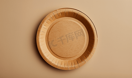 米色背景上由回收材料制成的空圆形棕色一次性盘子