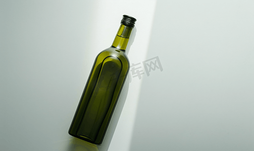 玻璃透明瓶子摄影照片_躺在旁边的绿色瓶子里上面有白色的橄榄油