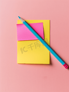 桌面视图上粉红色背景信纸上的粘便纸和彩色铅笔