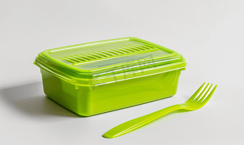 白色背景上带刀叉的绿色塑料食品容器