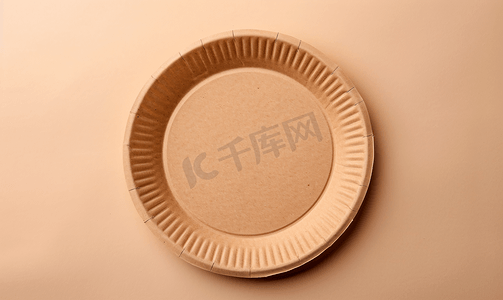 盘子套装摄影照片_米色背景上由回收材料制成的空圆形棕色一次性盘子