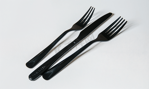 白色背景上隔离的一次性黑色塑料叉子和刀子