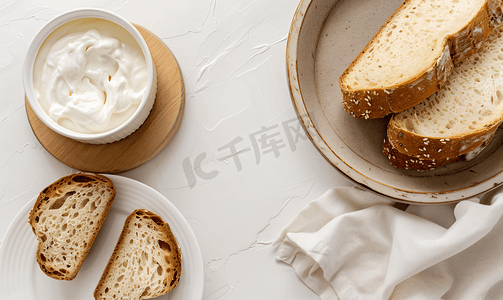 牛奶软面包摄影照片_容器中的牛奶奶油和盘子中的面包的顶视图