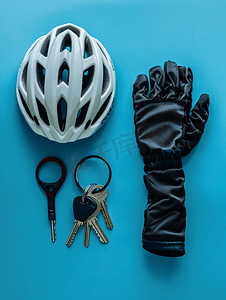 橡胶绝缘手套摄影照片_蓝色背景上带钥匙和手套的自行车头盔锁