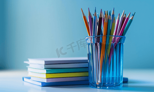 一盆植物摄影照片_蓝色玻璃中的一堆笔记本彩色铅笔