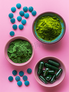 粉红色垂直视图中碗中的排毒和抗氧化剂抹茶粉和螺旋藻丸