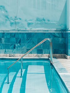 游泳池角落有大理石边框、蓝色陶瓷墙和泳池梯子