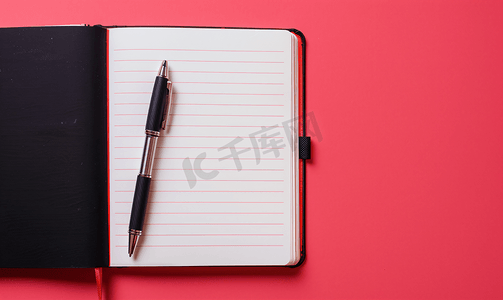 粉红色背景上放着一本打开的笔记本上面有一支笔