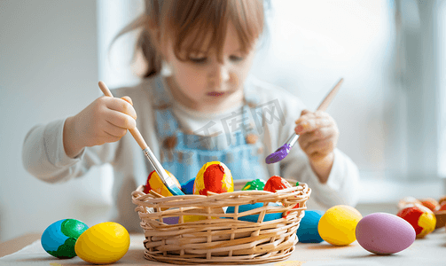 装饰彩绘摄影照片_孩子用彩色颜料给鸡蛋上色然后把它们放进篮子里复活节内容