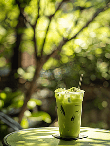 果汁咖啡摄影照片_花园桌子上玻璃杯中的冰绿茶拿铁