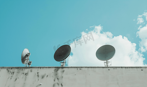 蓝天多云背景建筑物上的黑色卫星天线或电视天线