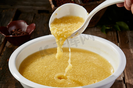 红薯米粥摄影照片_白色瓷盆装的黄金奶汤小米粥