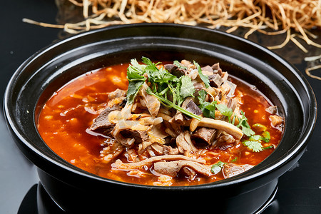 餐饮的美食摄影照片_黑色背景上的砂锅香辣红油羊杂煲