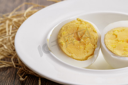 煮熟的鸡蛋摄影照片_木质底板上的白瓷碟装着的蛋黄绵密蛋白细嫩的特产由鸡蛋