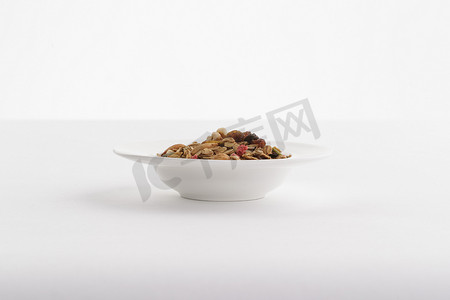 坚果零食背景摄影照片_自制的水果坚果混合燕麦铺洒摆放在桌子上