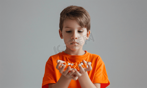 一个穿橙色衬衫的孩子手掌里拿着很多药丸